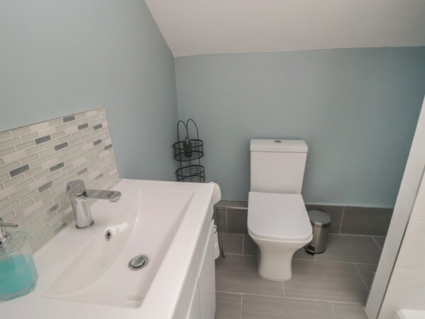 A bathroom with a white sink, a toilet, and a tiled floor. - Ruby's Retreat (Filey)