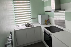 A compact kitchen with a sink, a small refrigerator, a stove, and a window with blinds. - Apartment Sleeps 4 Near Southampton City Centre (Southampton)