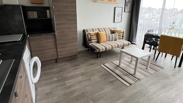 Een moderne woonkamer met een bank, salontafel en een eethoek.