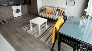 Een knus woongedeelte met een kitchenette, een bank, een salontafel en een eettafel.