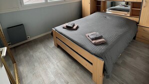Een slaapkamer met een bed, een raam, een kledingkast en een spiegel.