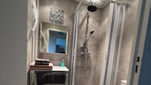 Een moderne badkamer met douche, toilet en wastafel.