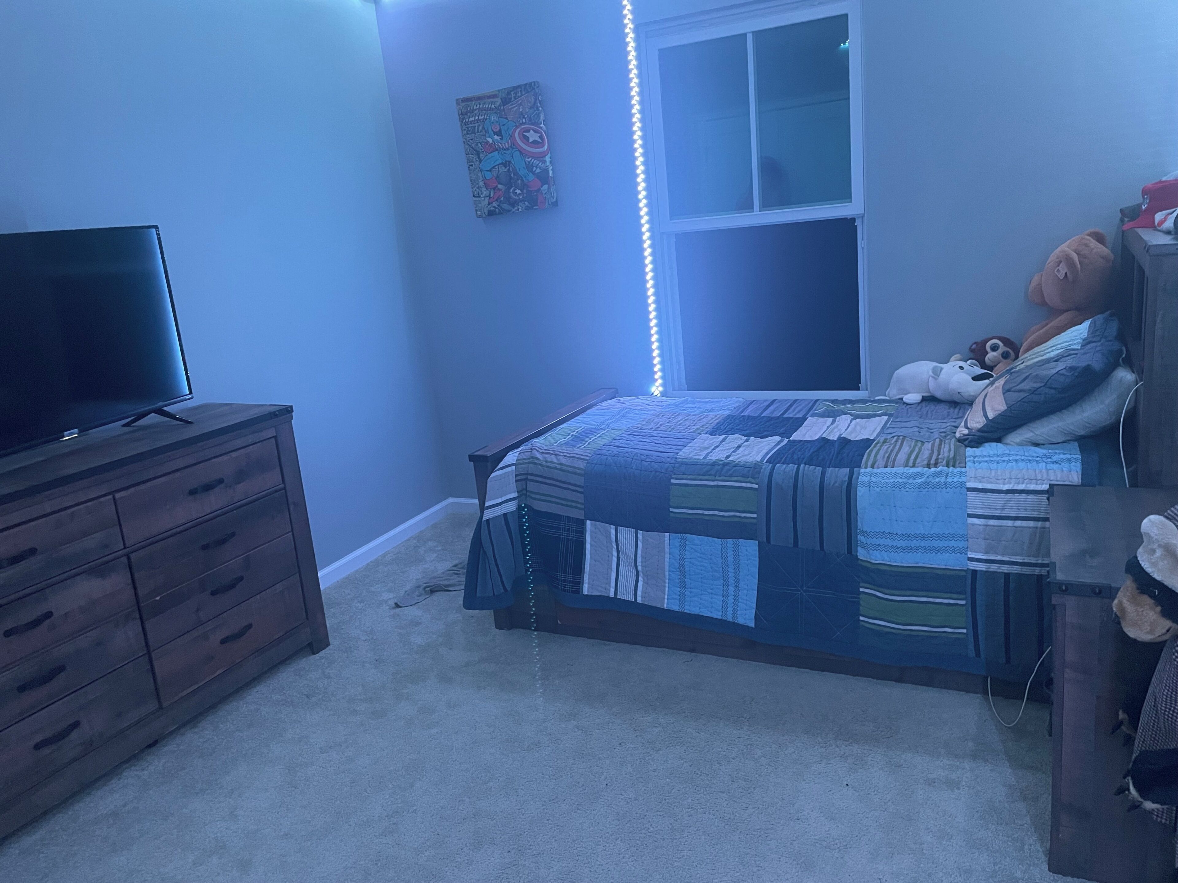 A bedroom with a bed, a dresser, a television, and a window.