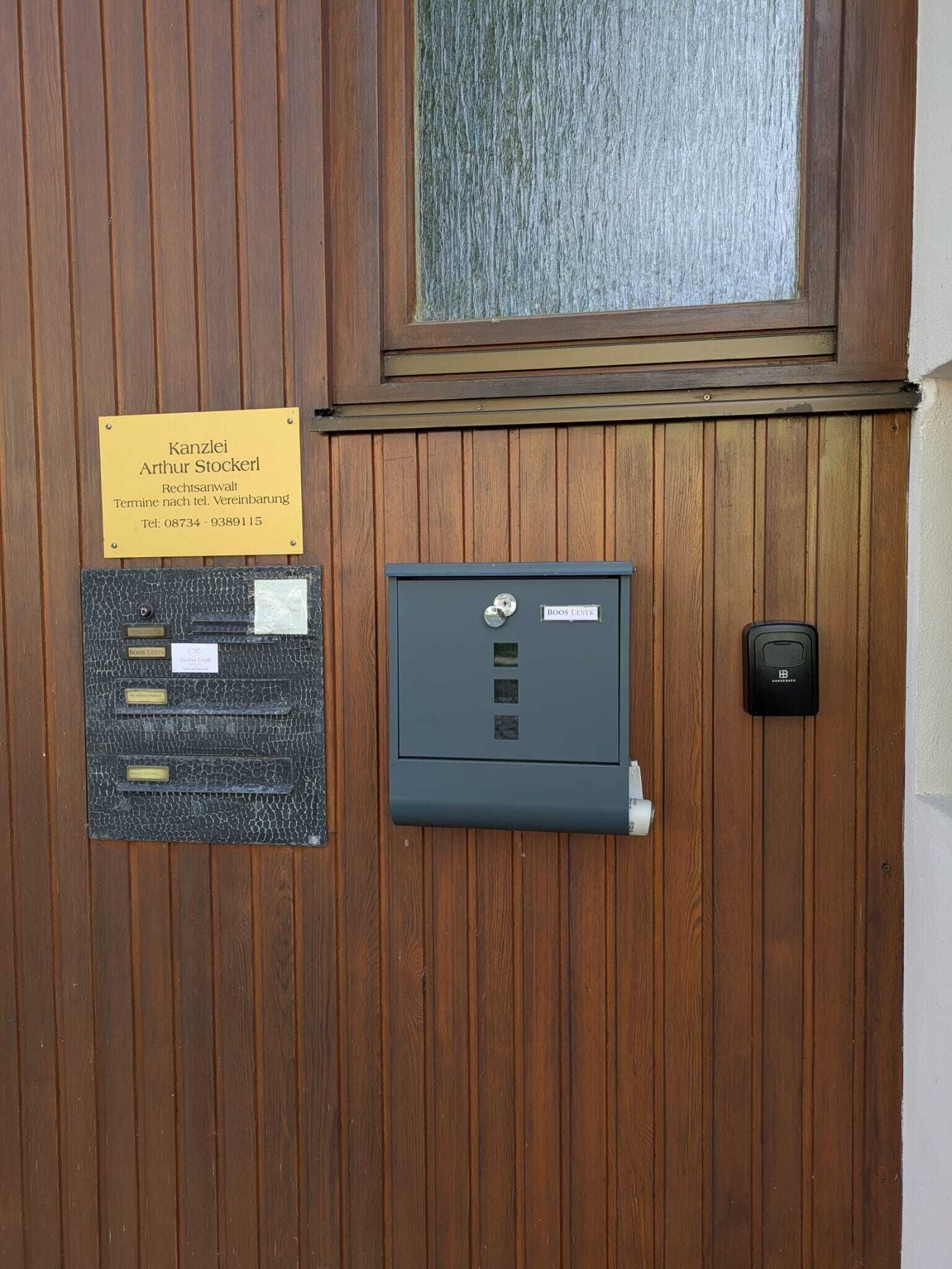 Une porte en bois avec une plaque, un coffre-fort en métal et un sonnette.