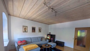 Una sala de estar con un sofá, una mesita, una estantería y una puerta con cristal satinado.