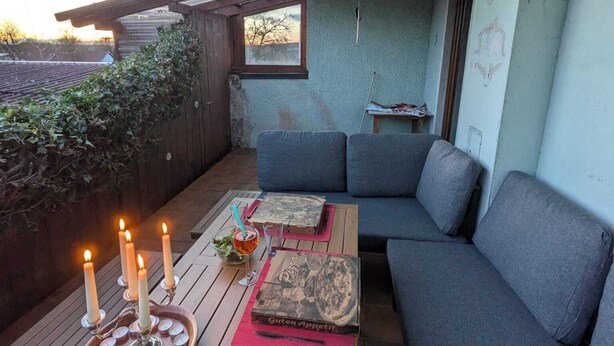 Un rincón al aire libre acogedor con una mesa, cojines y velas.