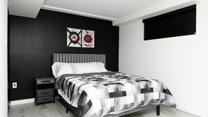 Une chambre à coucher comprenant un lit, une table de chevet, une commode et deux œuvres d’art accrochées au mur.
