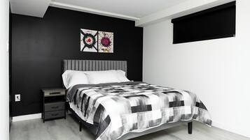 Une chambre à coucher comprenant un lit, une table de chevet, une commode et deux œuvres d’art accrochées au mur.