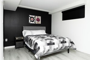 Un dormitorio con cama, mesita de noche, cómoda y dos obras de arte colgadas en la pared.