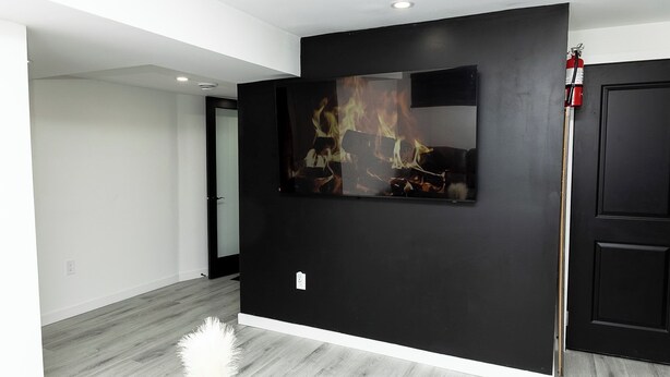 Une pièce moderne avec un mur d’accent noir, une œuvre d’art accrochée et une porte blanche.