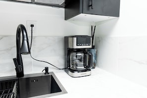 Una cocina con cafetera integrada, un lavabo y un grifo moderno.