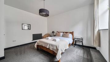 Un dormitorio moderno con cama, mesita de noche, lámpara y lámpara colgante.