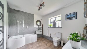 A modern bathroom with a bathtub, toilet, and shower area. - Stunning Retreat in Matlock Bath (Matlock)