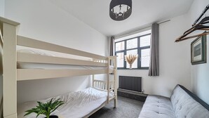 A bunk bed room with a radiator, a window with curtains, a plant, and a sofa. - Stunning Retreat in Matlock Bath (Matlock)