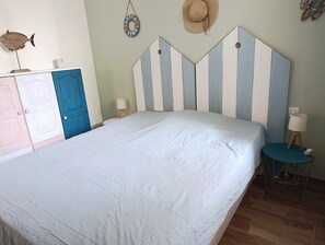 Une chambre à coucher avec un lit, une commode, une lampe et un élément de décoration murale.