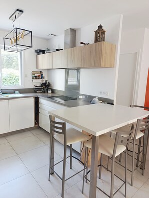 Une cuisine moderne avec des meubles blancs, un îlot central et un coin repas avec des chaises.