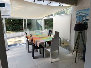 Un espace extérieur aménagé pour prendre les repas, avec une table, des chaises, une lampe et une vue sur la verdure.