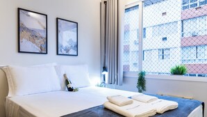 A hotel room with a bed, two framed pictures, a bottle of champagne, and towels on the bed. - Beira-Mar - Canal 4 - AC (Santos)