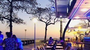 An outdoor dining area with tables and chairs, a bar area with a counter, and a view of the beach. - Beira-Mar - Canal 4 - AC (Santos)