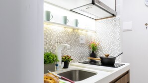 A modern kitchen with a white countertop, a sink, a stove, and a backsplash with a mosaic tile pattern. - Beira-Mar - Canal 4 - AC (Santos)
