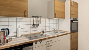 A modern kitchen with wooden cabinets, a stainless steel sink, and a built-in oven. - Modo Apartments Erkelenz | Pool and sauna (Erkelenz)