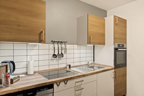 A modern kitchen with wooden cabinets, a stainless steel sink, and a built-in oven. - Modo Apartments Erkelenz | Pool and sauna (Erkelenz)