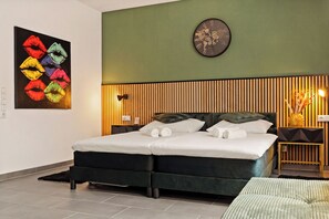 A double bed with a wooden headboard, a world map clock, and a colorful artwork of lips on the wall. - Modo Apartments Erkelenz | Pool and sauna (Erkelenz)