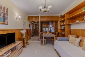Ein gemütlicher Wohnbereich mit Fernseher, Esstisch, Küchenzeile und einem Bett.