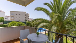 A balcony with a table and chairs, a small plant, and a view of a building and palm trees. - #366 Cozy 1BR Retreat | Private Balcony (Albufeira)