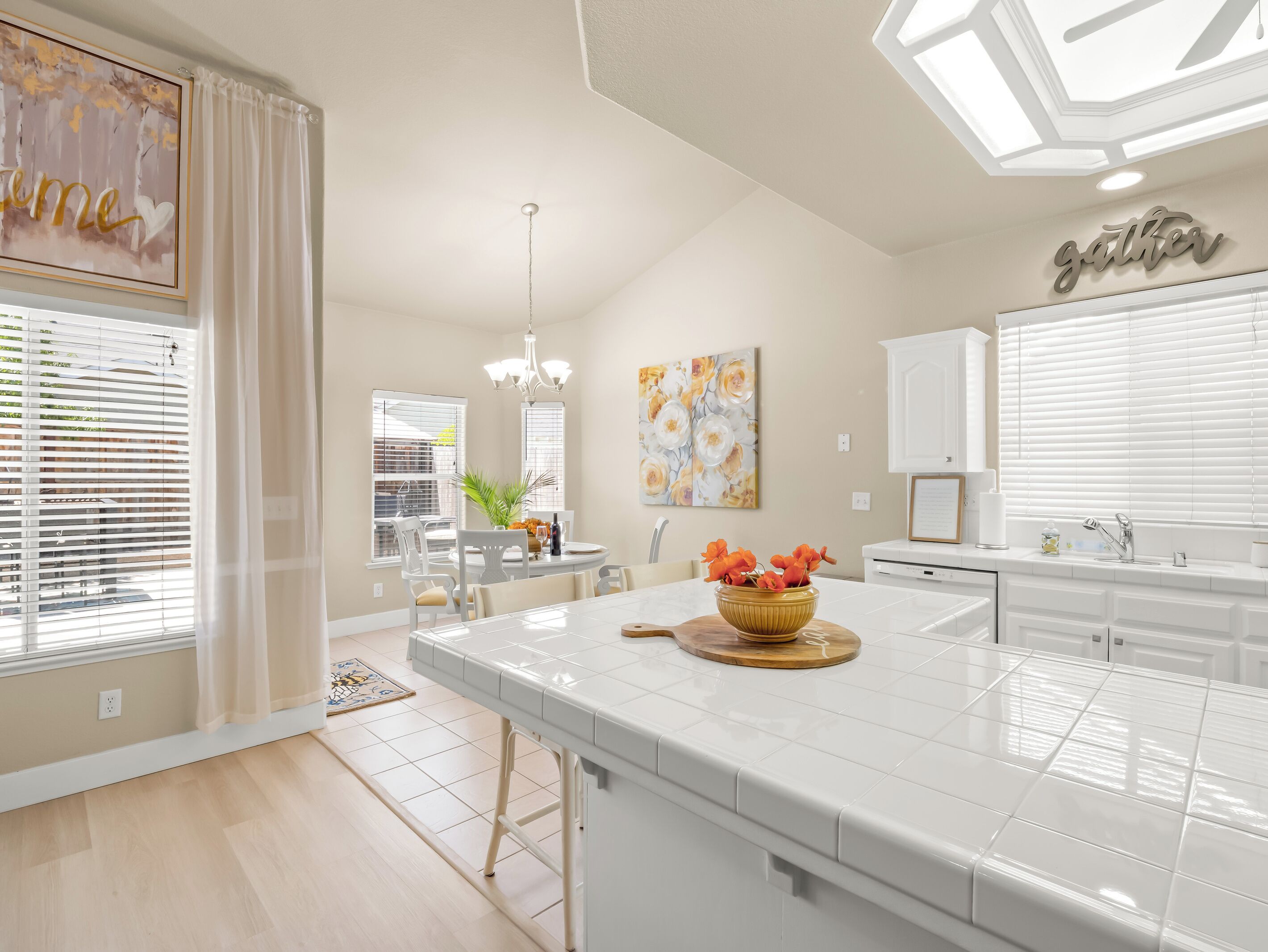 A modern kitchen with a central island, white cabinetry, and a dining area with a table and chairs.