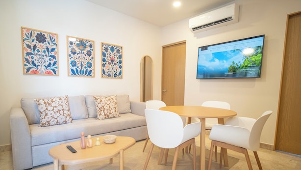 A living room with a sofa, a coffee table, a TV, and a wall-mounted air conditioner. - Abba Suites Playa Del Carmen (Playa del Carmen)