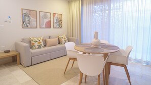 Una sala de estar moderna con un sofá, sillas, una mesa de centro y obras de arte en la pared.