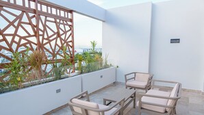 Un balcón con celosía de madera, mobiliario exterior y vistas de la ciudad.