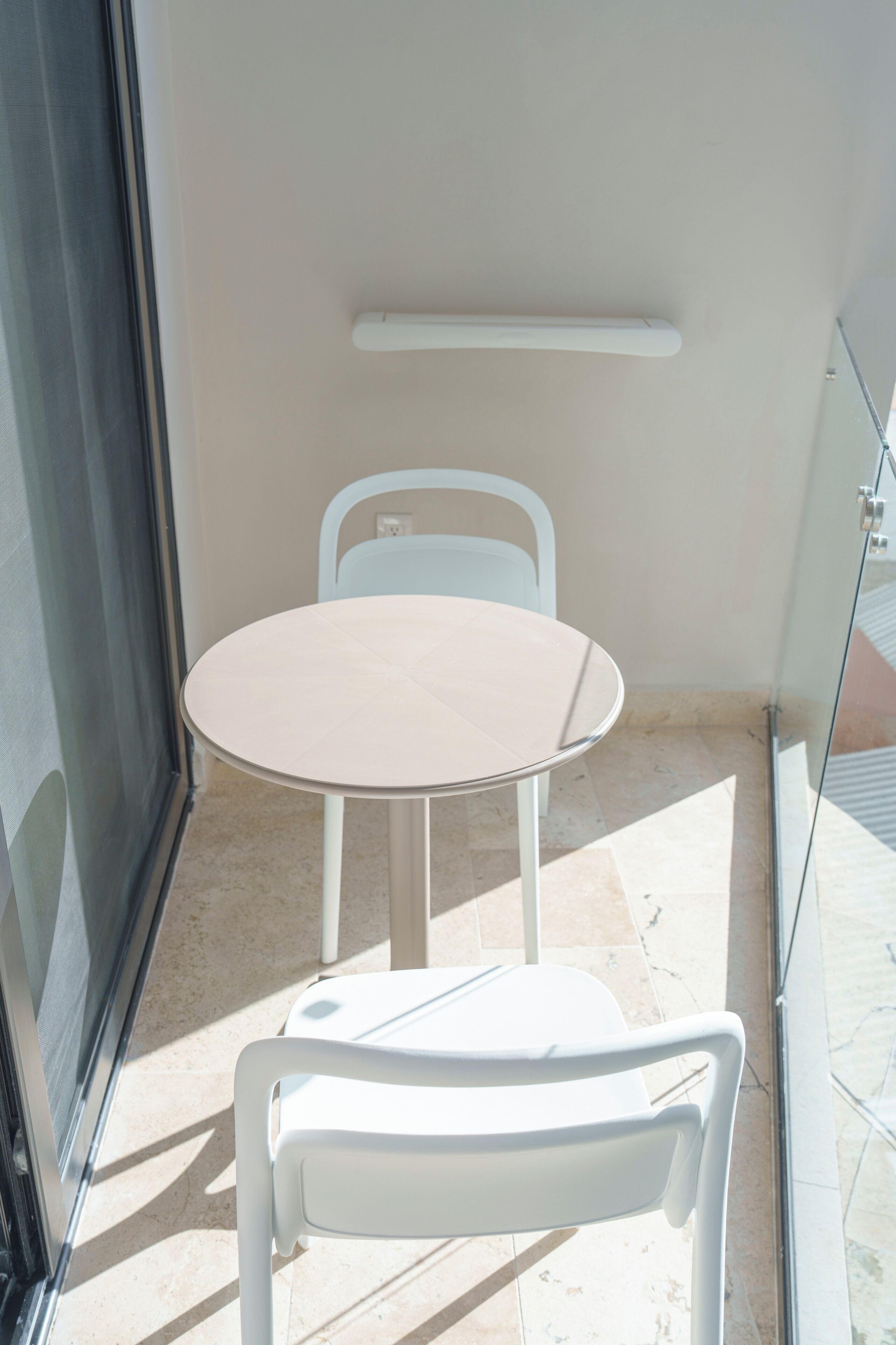 Een kleine ronde tafel met een stoel, een plafondlamp en een glazen deur.