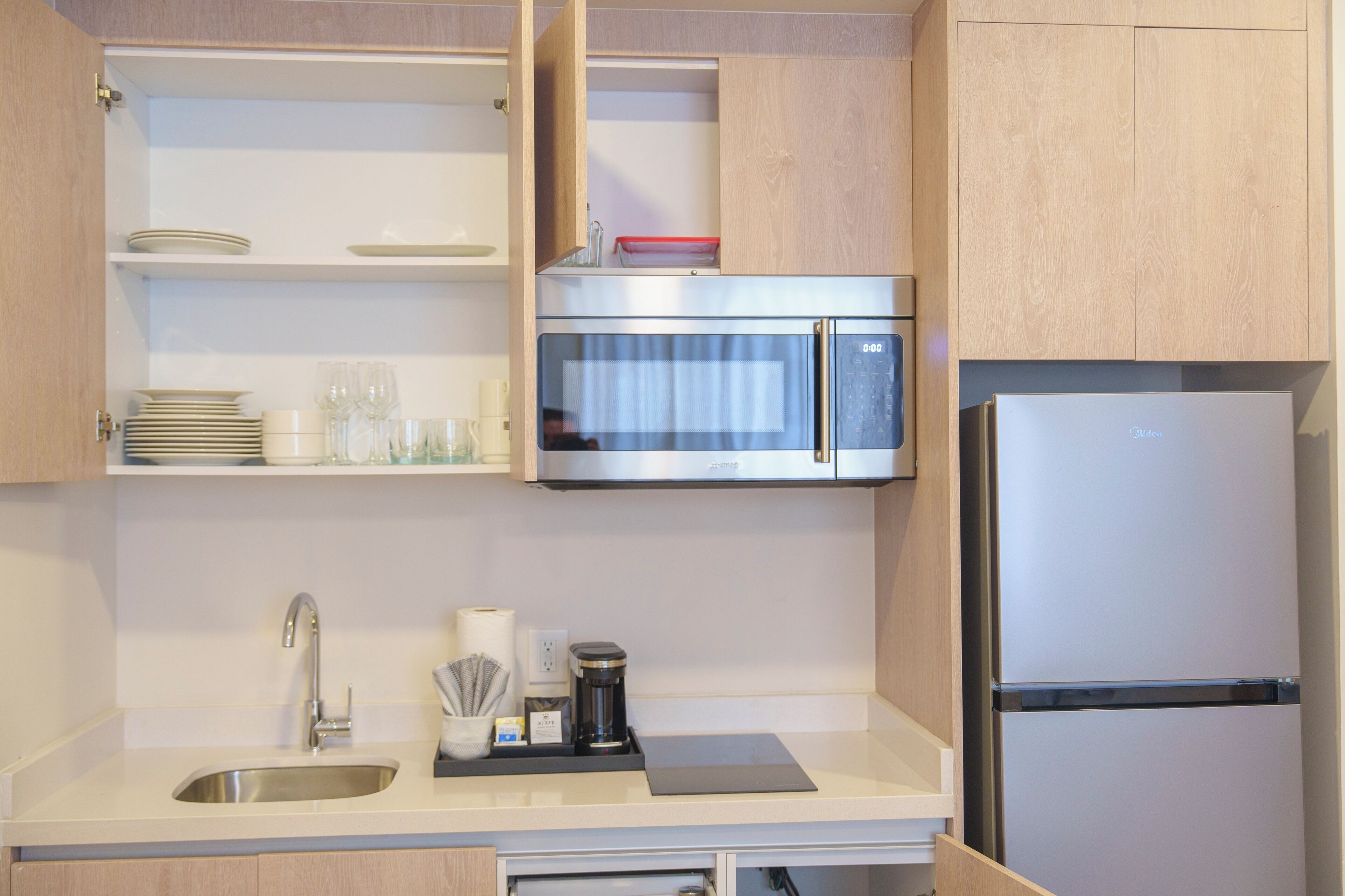 Eine moderne Küche mit Spüle aus Edelstahl, einer Mikrowelle und einem Kühlschrank.