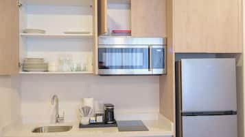 Eine moderne Küche mit Spüle aus Edelstahl, einer Mikrowelle und einem Kühlschrank.