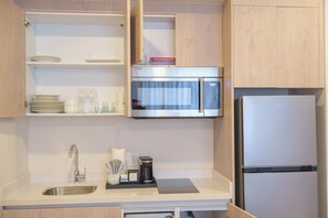 A modern kitchen with a stainless steel sink, a microwave, and a refrigerator.