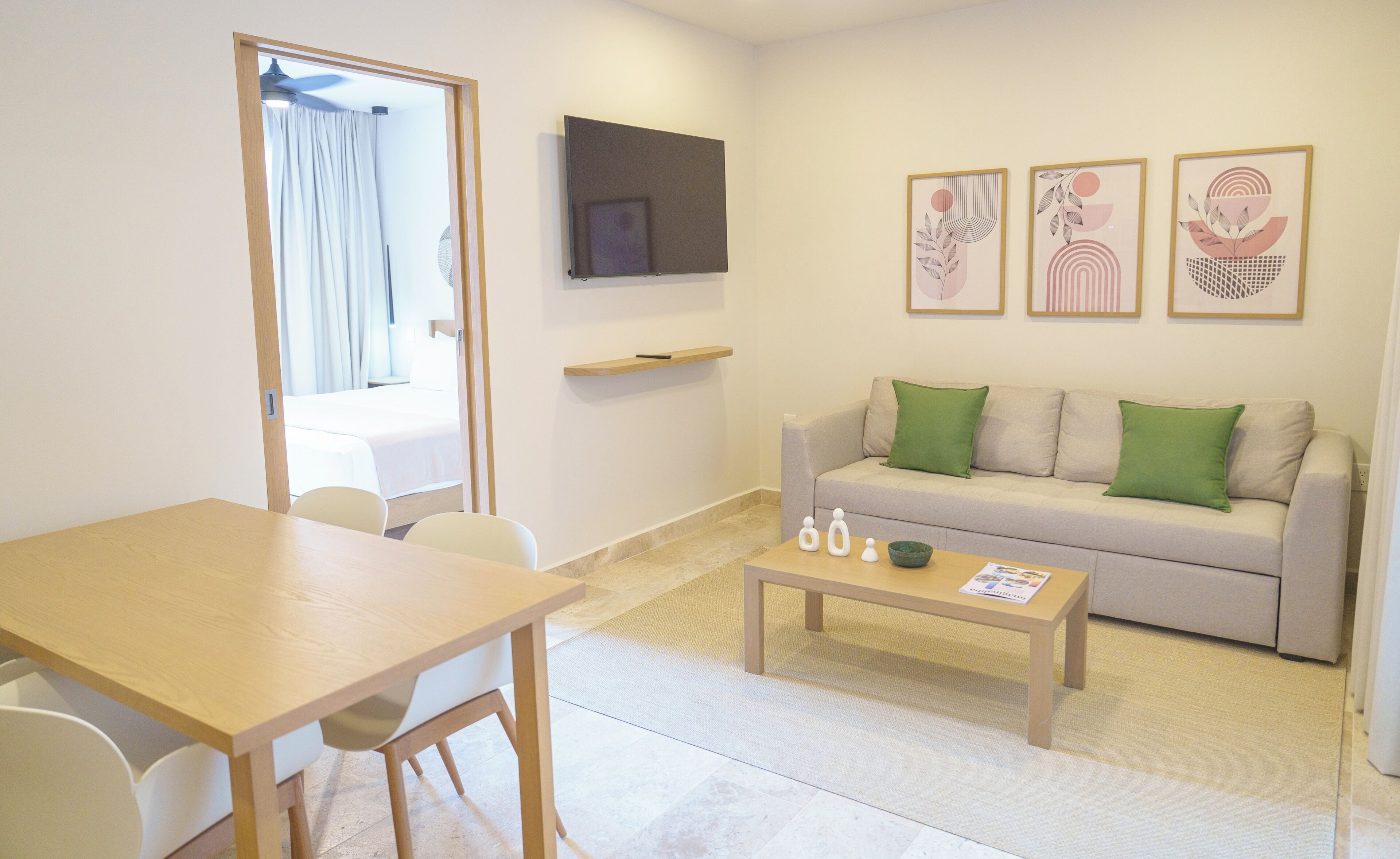 Una sala de estar moderna con un sofá, una mesa de centro, un televisor montado en la pared y un comedor con sillas y una mesa.