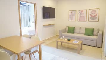 Una sala de estar moderna con un sofá, una mesa de centro, un televisor montado en la pared y un comedor con sillas y una mesa.