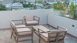 A rooftop terrace with a table and four chairs, overlooking a cityscape with buildings and a clear sky. - Abba Suites Playa Del Carmen (Playa del Carmen)