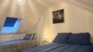 A bedroom with two beds, a skylight, a chandelier, and a painting. - Cottage Sleeps 8 - Garden, Bbq, Pet-friendly (Warwick)