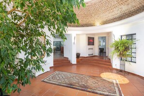 A spacious interior with a tiled floor, a patterned rug, and a large potted plant. - Casa Seteais (Carvoeiro)