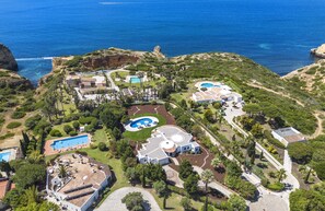 An aerial view of a coastal resort with multiple swimming pools, a large central building, and surrounding greenery. - Casa Seteais (Carvoeiro)