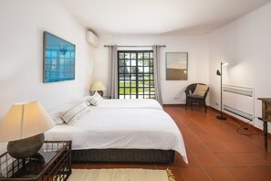A bedroom with a bed, a chair, a lamp, and a radiator. - Casa Seteais (Carvoeiro)