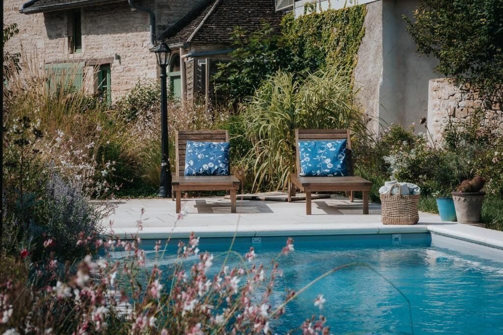 Un espace aménagé au bord de la piscine, avec deux chaises longues en bois et un panier en osier.