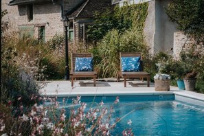 A poolside area with two wooden lounge chairs and a wicker basket. - Maison Tassigny (Meursault)