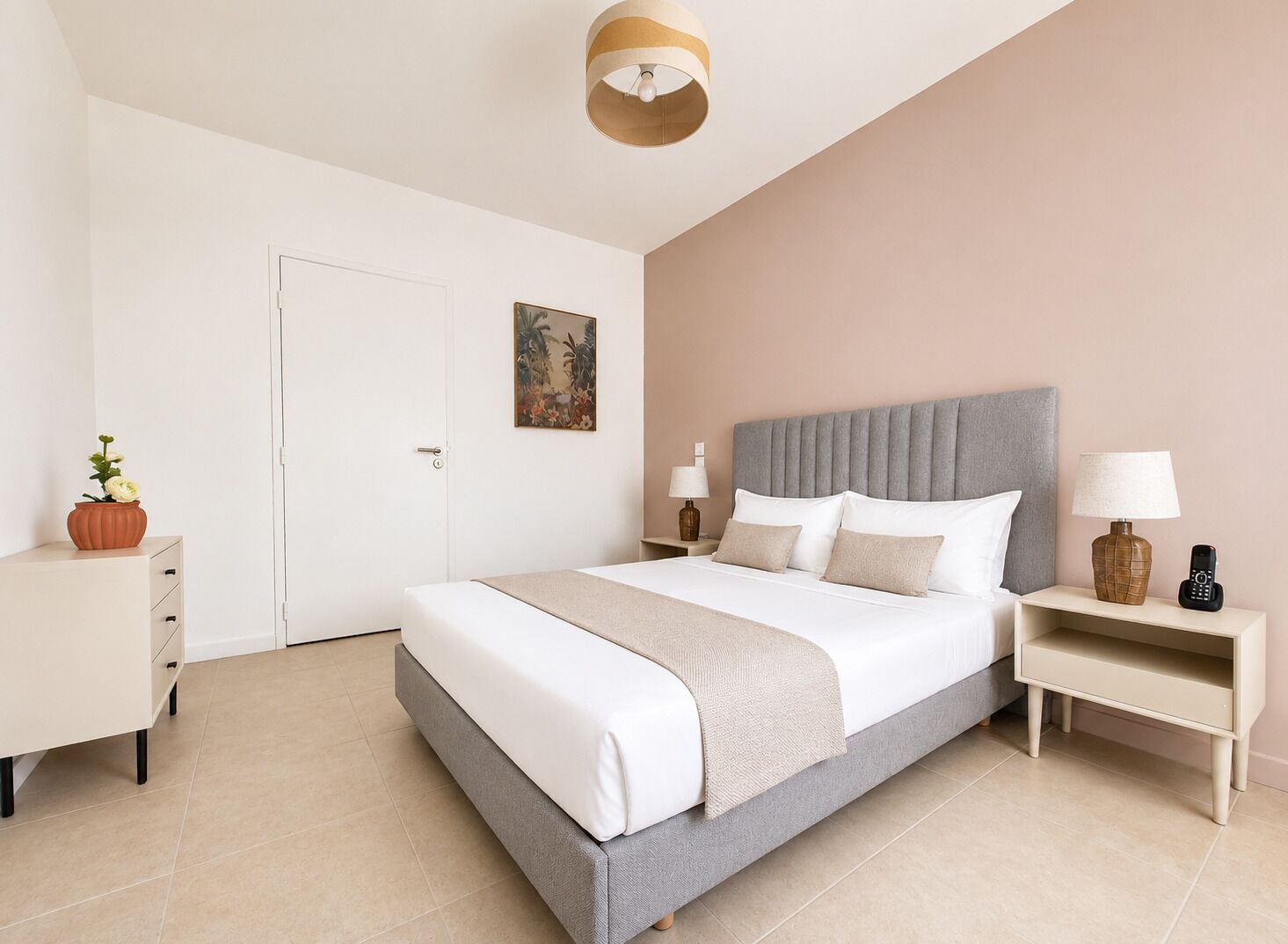 Een hotelkamer met een bed, nachtkastjes, een deur, een schilderij en een potplant.