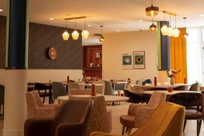 A hotel lobby with multiple seating areas, a coffee bar, and a visible espresso machine.