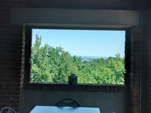A room with a brick wall, a window with a view of trees and a distant landscape. - Holiday Home 'Casa Centomila Volte Benvenuti' with Private Terrace (Tigliole)
