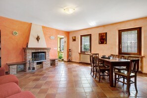 A spacious living area with a fireplace, a dining table, and chairs. - Casa 'Centomila Volte Benvenuti' (Tigliole)